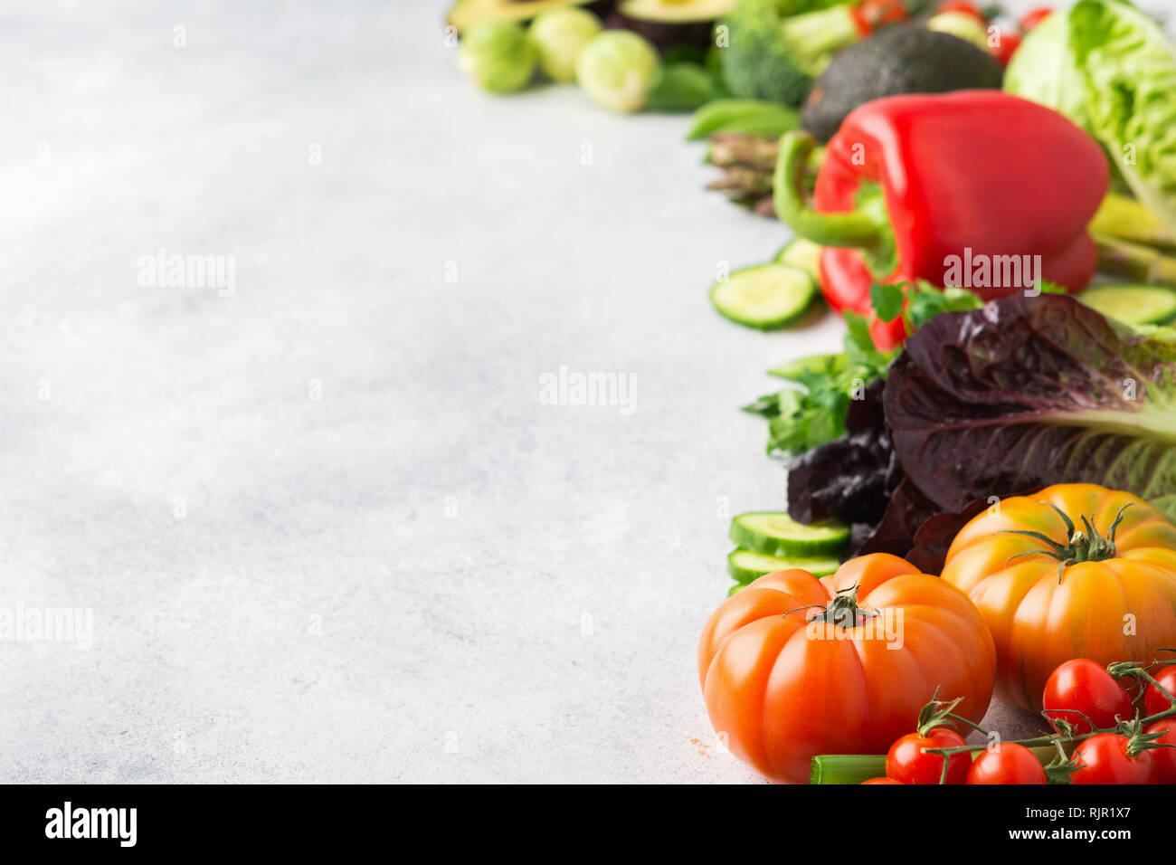 Gli ingredienti freschi per insalata e pomodori cetrioli insalata di avocado pepe prezzemolo cipollina broccoli piselli sul tavolo bianco, spazio di copia Foto Stock