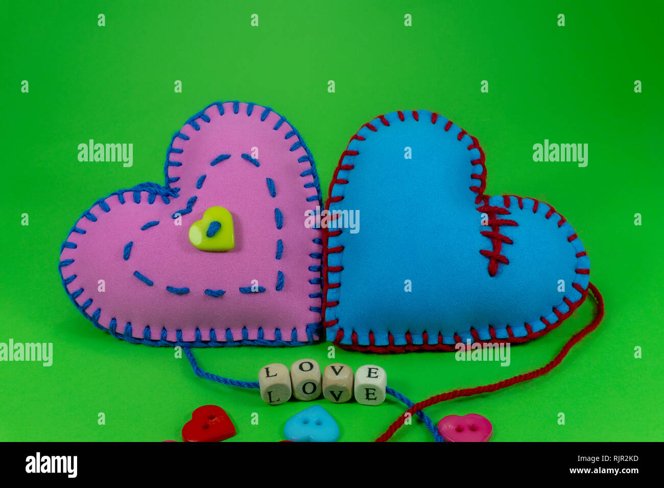 Mano tessile cucita nei cuori la parola amore su blocchi filettato su stringhe su verde sfondo chroma key per rapporto romantico, il giorno di San Valentino, bro Foto Stock