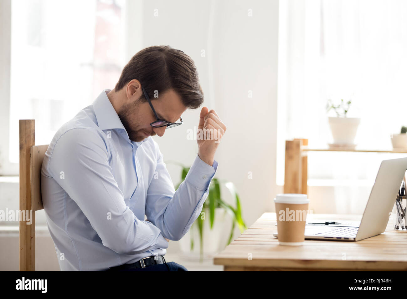 Frustrato uomo sensazione perdente seduta vicino laptop sconvolto dal fallimento Foto Stock