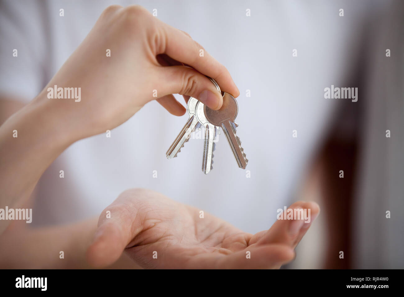 Broker mano che tiene le chiavi dando al nuovo proprietario di casa, primo piano Foto Stock