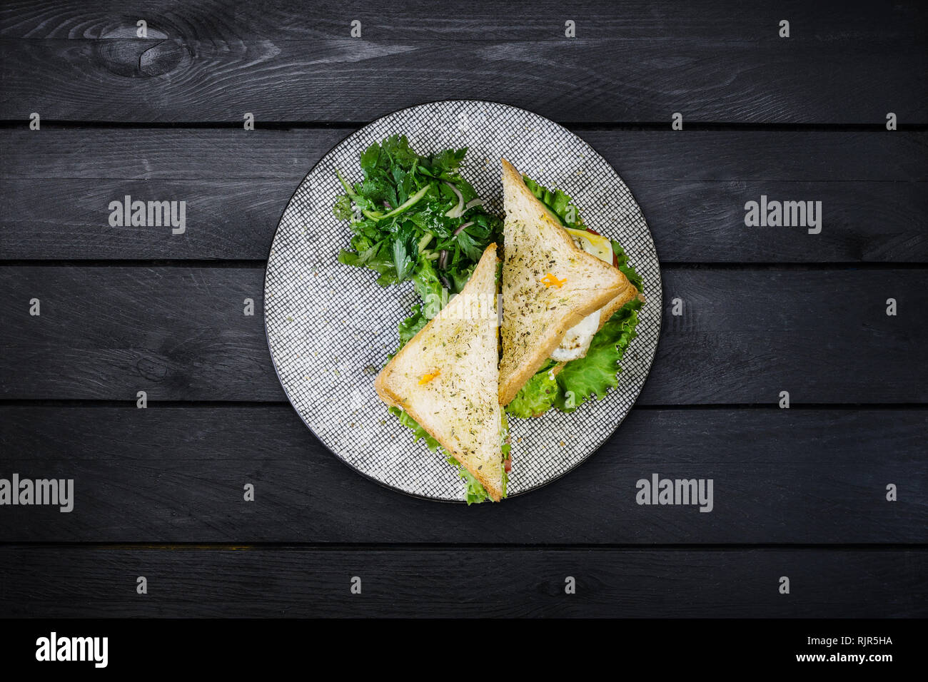 Sandwich di Pollo e le verdure su una piastra di ceramica. Nero su sfondo di legno, vista dall'alto Foto Stock
