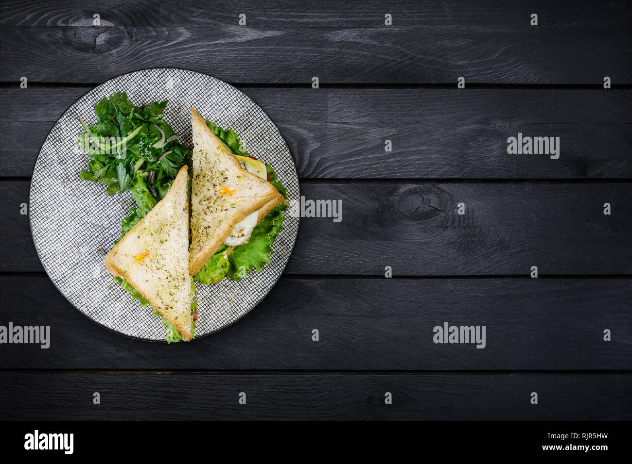 Sandwich di Pollo e le verdure su una piastra di ceramica. Nero su sfondo di legno. Vista superiore, copia dello spazio per il testo Foto Stock