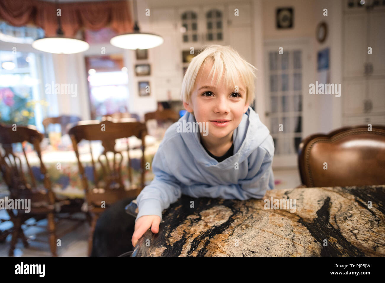 Ragazzo sporgersi in avanti sul divano Foto Stock