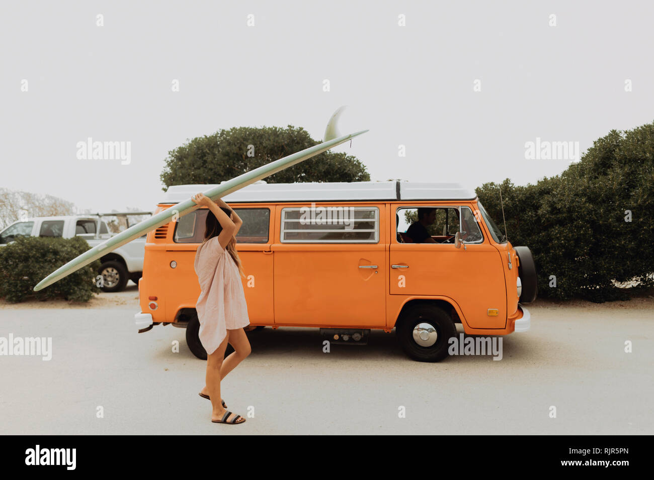 Giovani femmine surfer che trasportano le tavole da surf in spiaggia parcheggio, Jalama, Ventura, CALIFORNIA, STATI UNITI D'AMERICA Foto Stock