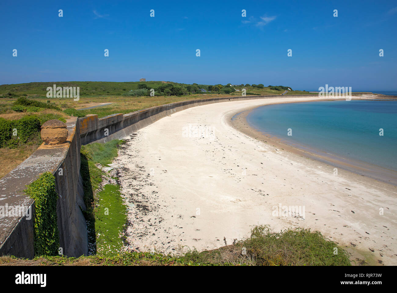 Vista nord est lungo la baia Longis, Alderney, mostrando il massiccio tedesco costruito contro la parete del serbatoio. Foto Stock