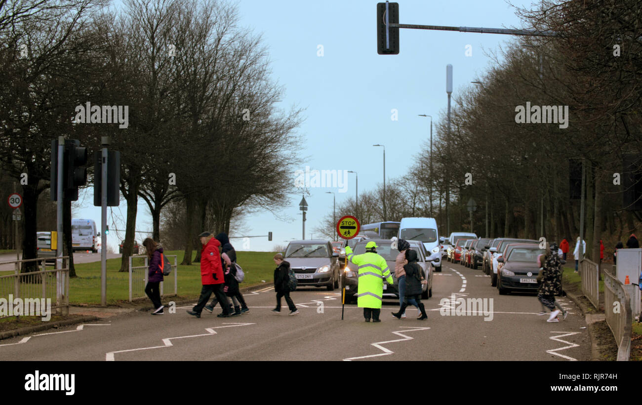 A82 Great Western Road, Glasgow, Scotland, Regno Unito un lecca-lecca lady aiuta gli allievi e i genitori attraverso un occupato A82 road Foto Stock