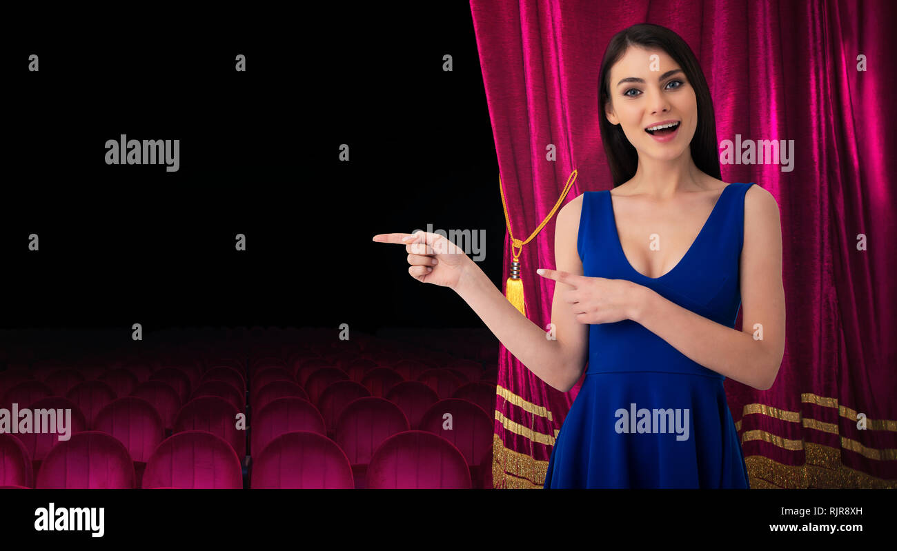 Bella donna di fronte tende rosse indica qualcosa circa il teatro mostra Foto Stock