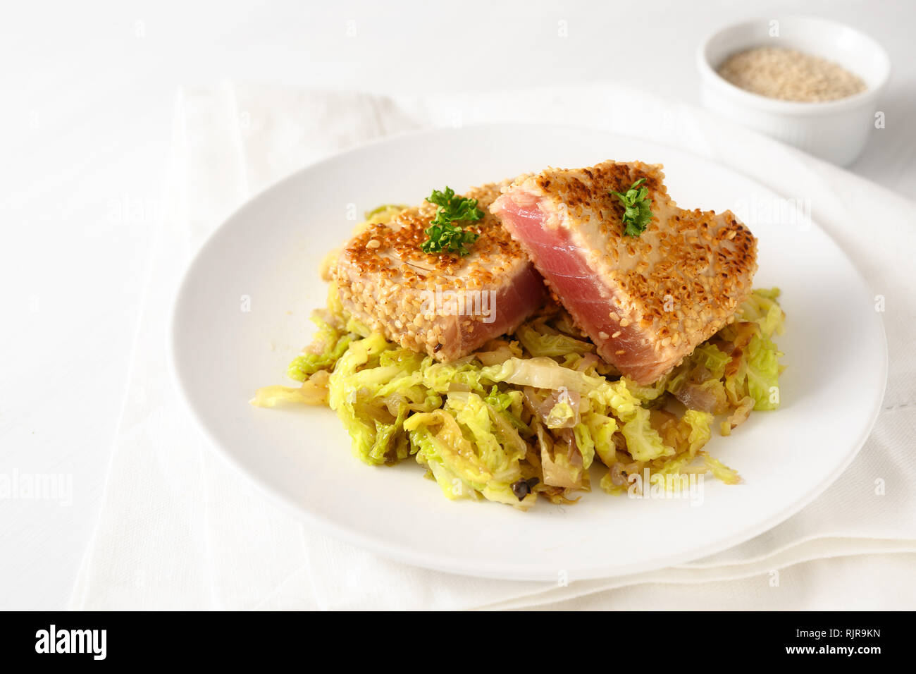 Arrosto di bistecca di tonno in semi di sesamo con verze vegetale, su una piastra su un tavolo bianco, spazio copia selezionata, focus, profondità di campo ridotta Foto Stock