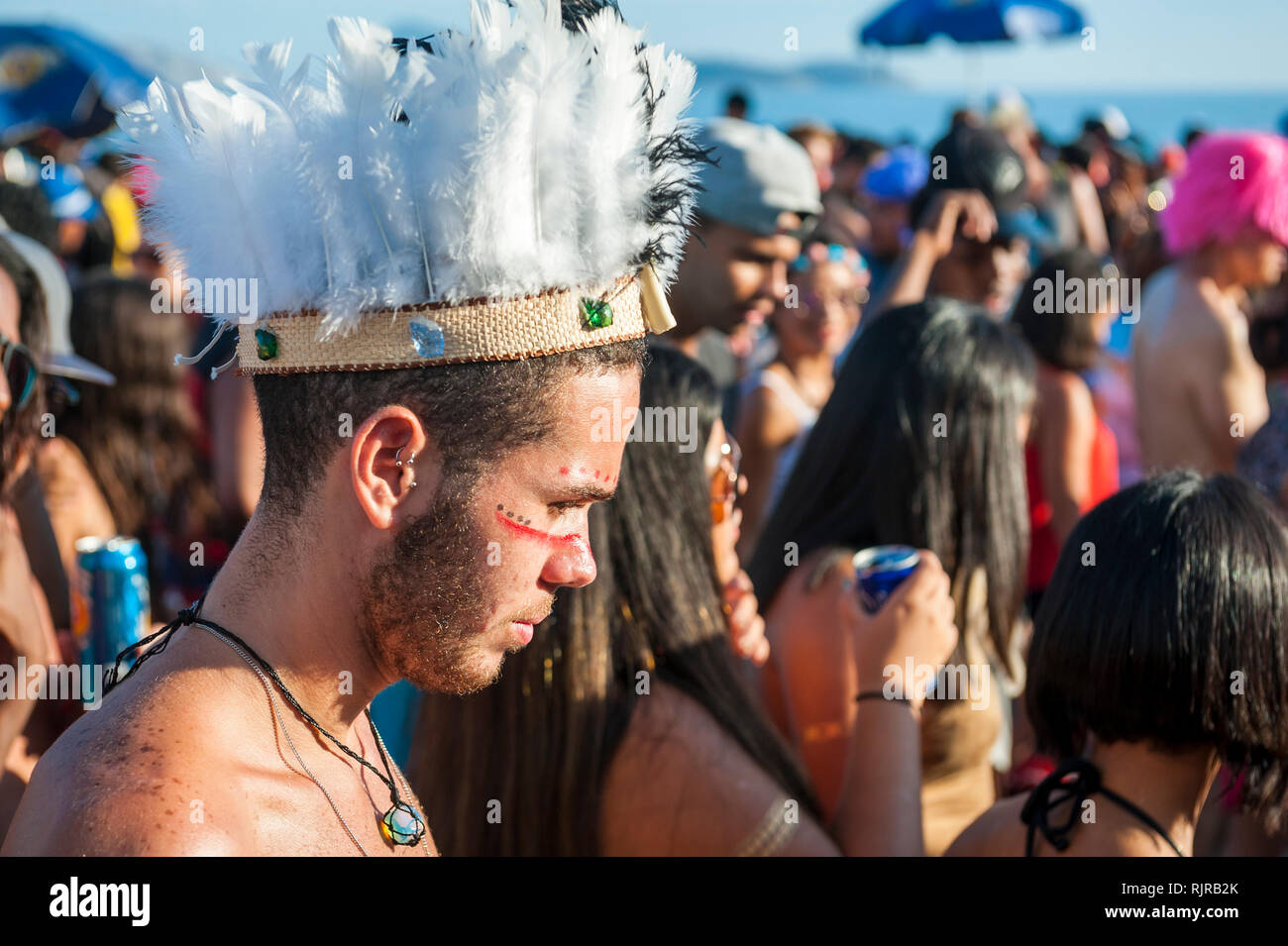 RIO DE JANEIRO - 28 febbraio 2017: un giovane brasiliano uomo abiti fino in Native American faccia la vernice e copricapo al Carnevale street party in Ipanema Foto Stock