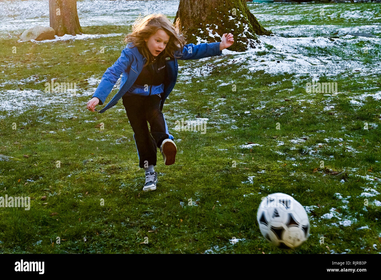 Giovani dai capelli lunghi ragazzo giocando con il pallone da calcio Foto Stock