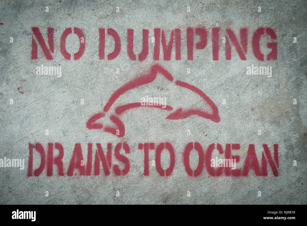 Nessun Dumping; scarichi per Ocean il messaggio di avvertimento con lo stampino di un delfino sulla semplice sfondo di calcestruzzo Foto Stock