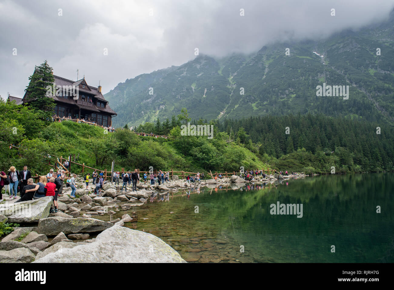 I turisti sedersi sul banco roccioso di Morskie Oko lago (l'occhio del mare) nelle montagne Tatra nel Parco nazionale dei Tatra,Piccola Polonia voivodato, Polan Foto Stock