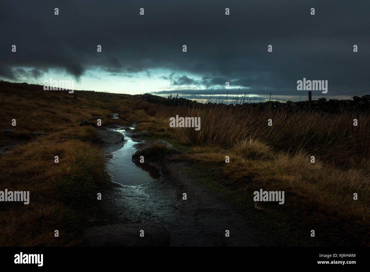 Un Wuthering Heights paesaggio tipo che mostra una brughiera bagnato con una pozzanghera riflettendo la luce nella distanza al di là di un cielo nuvoloso scuro Foto Stock