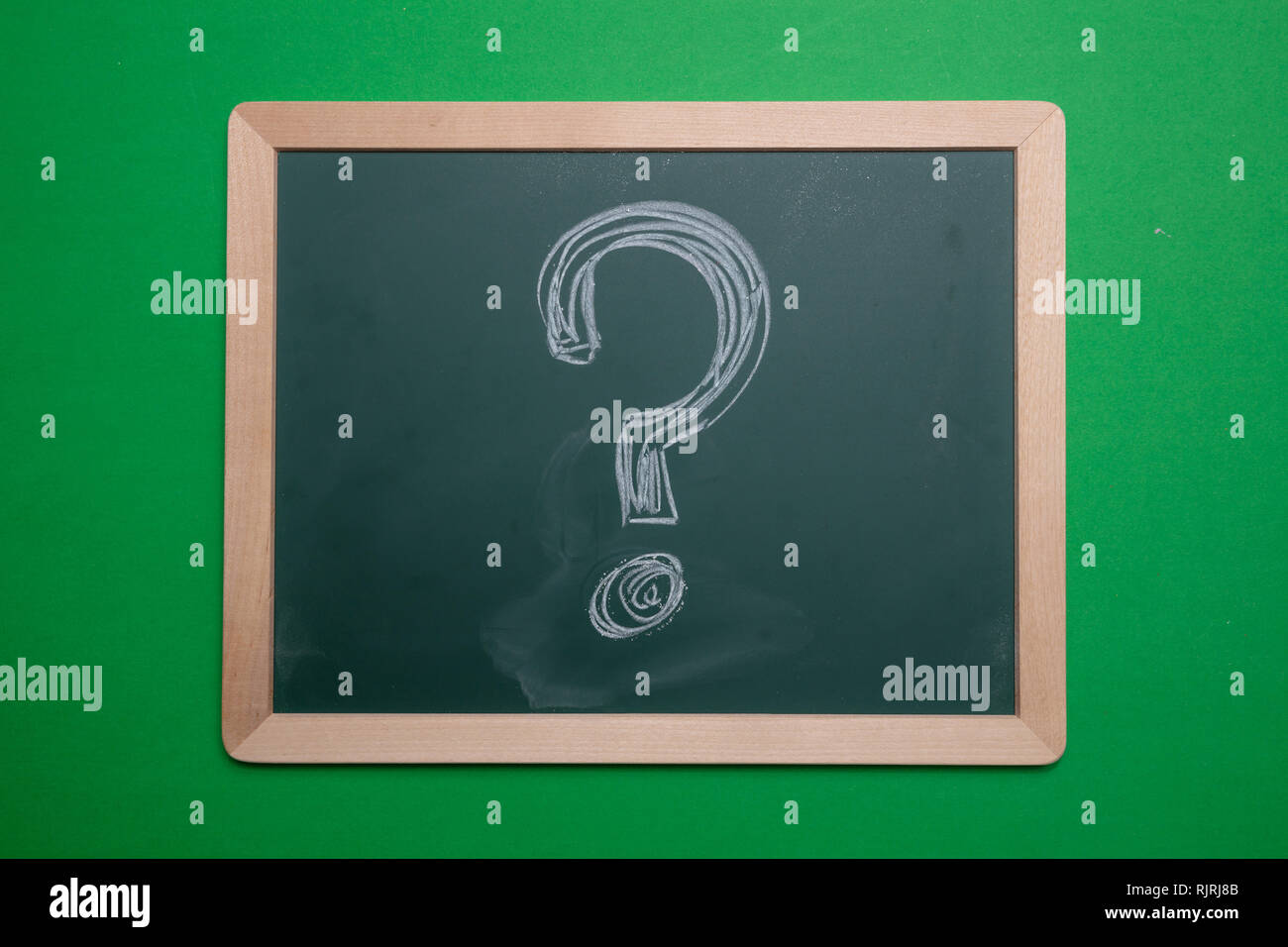 Punto interrogativo. Chalk del disegno a mano punto interrogativo forma sulla scheda verde con telaio in legno sfondo Foto Stock