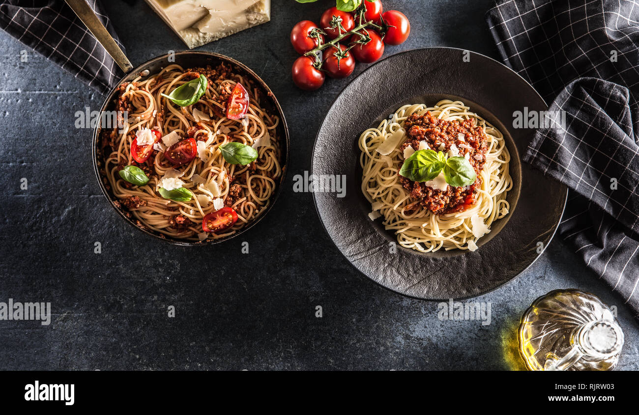 Parte superiore di vista la pasta italiana spaghetti alla bolognese in piastra e pan con pomodori e basilico Foto Stock