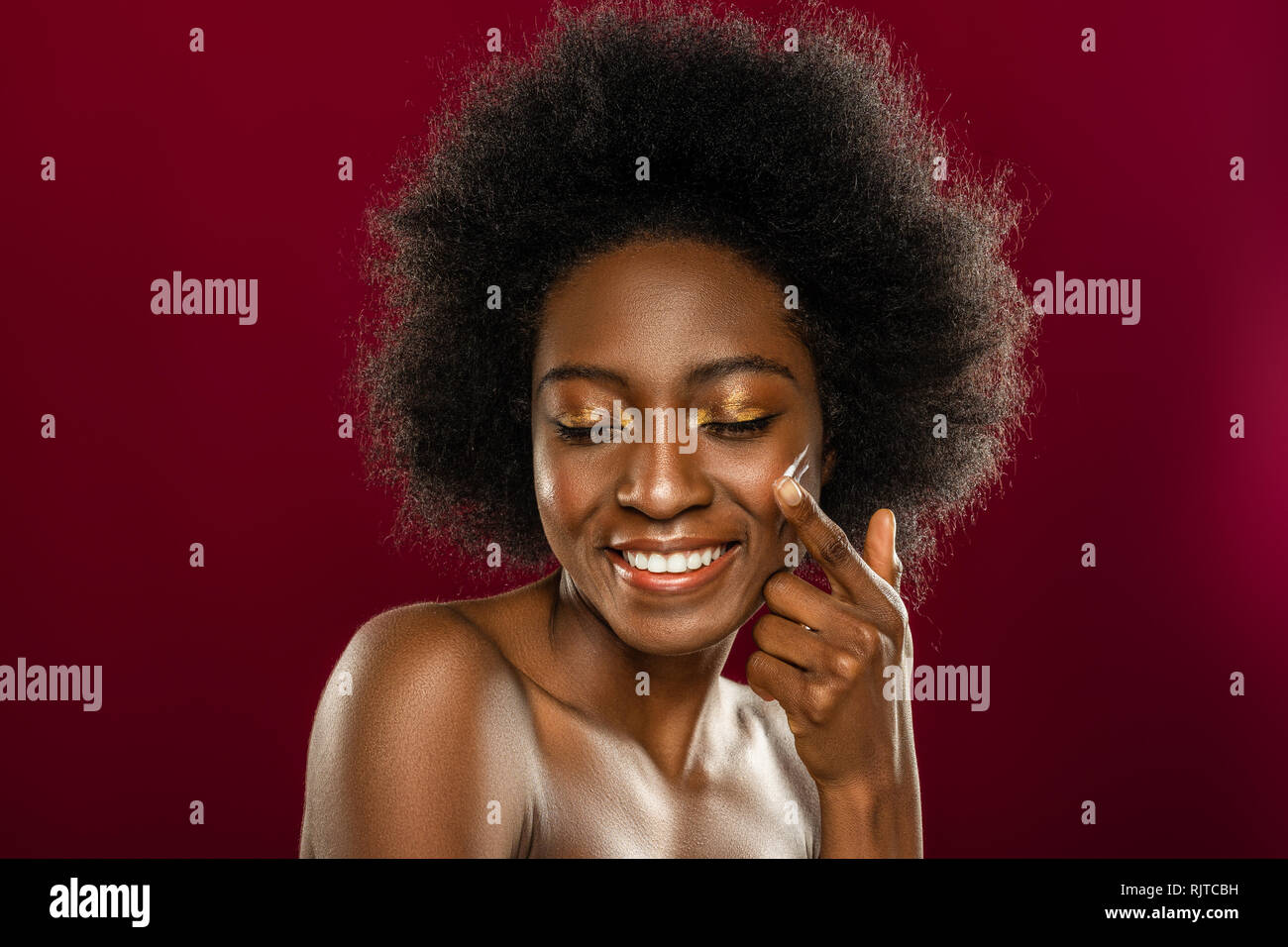 Faccia di un allegro giovane donna mentre l'applicazione di crema di latte Foto Stock