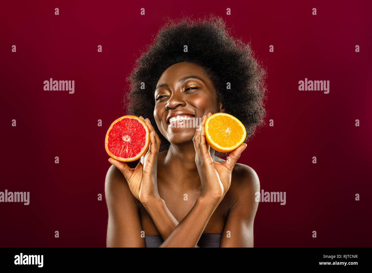 Felice bella donna che vi mostra le due metà di frutta Foto Stock Felice bella donna che vi mostra le due metà di frutta Foto Stock
