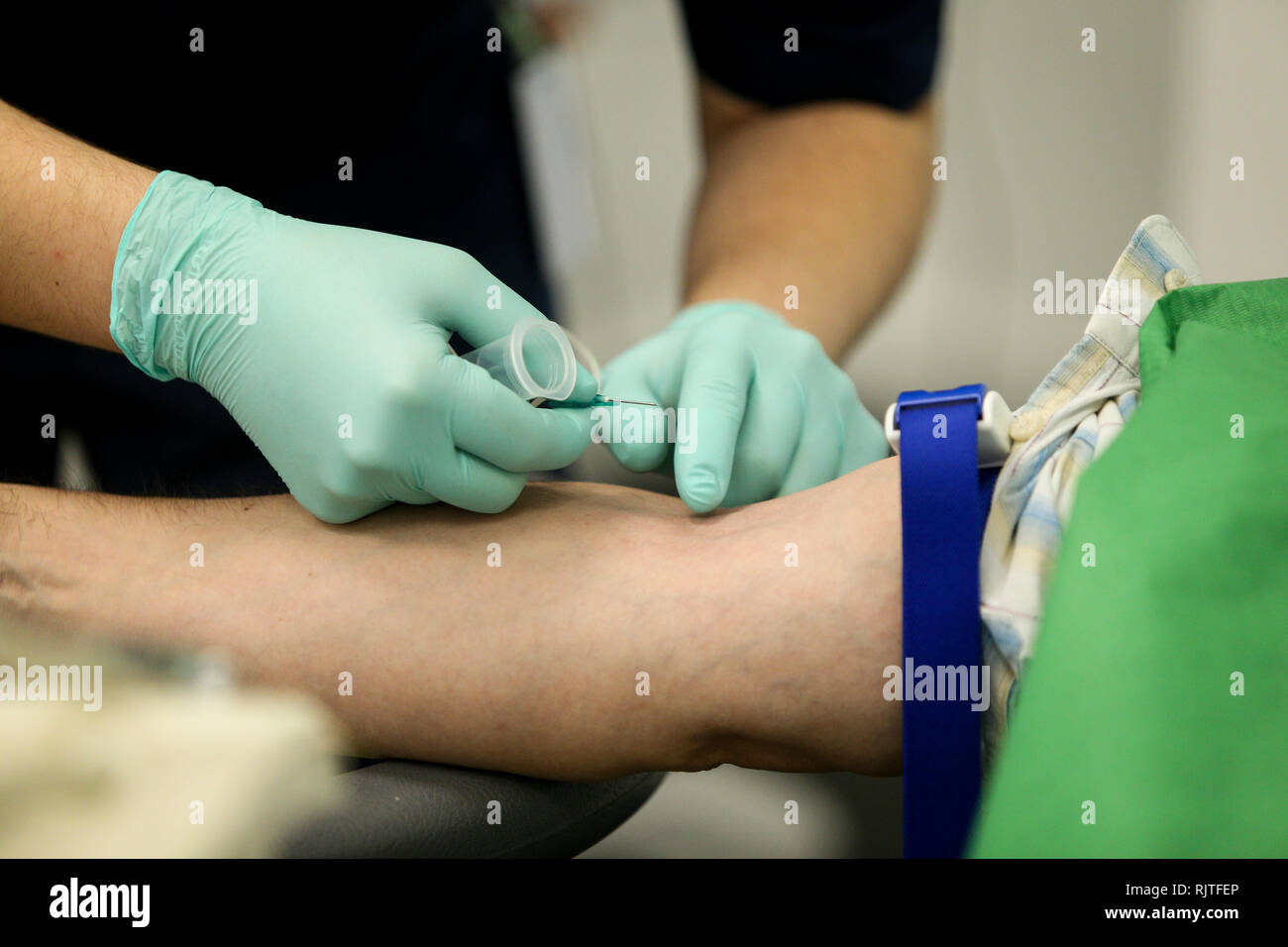 Dettagli con le mani di un medico, gomma da indossare i guanti chirurgici, preparandosi a prendere il sangue dalla vena di un paziente con un catetere Foto Stock