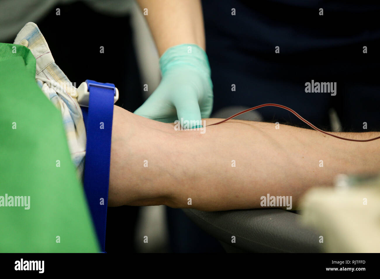 Dettagli con le mani di un medico, gomma da indossare i guanti chirurgici, prelievo di sangue dalla vena di un paziente con un catetere Foto Stock