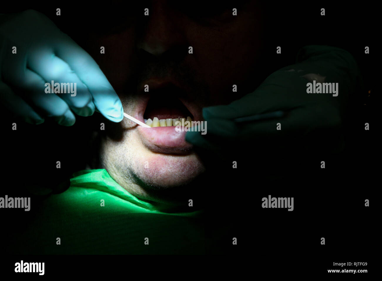 Dettagli con le mani di una donna dentista con i guanti chirurgici, lavorando con strumenti specifici all'interno della bocca di un paziente Foto Stock