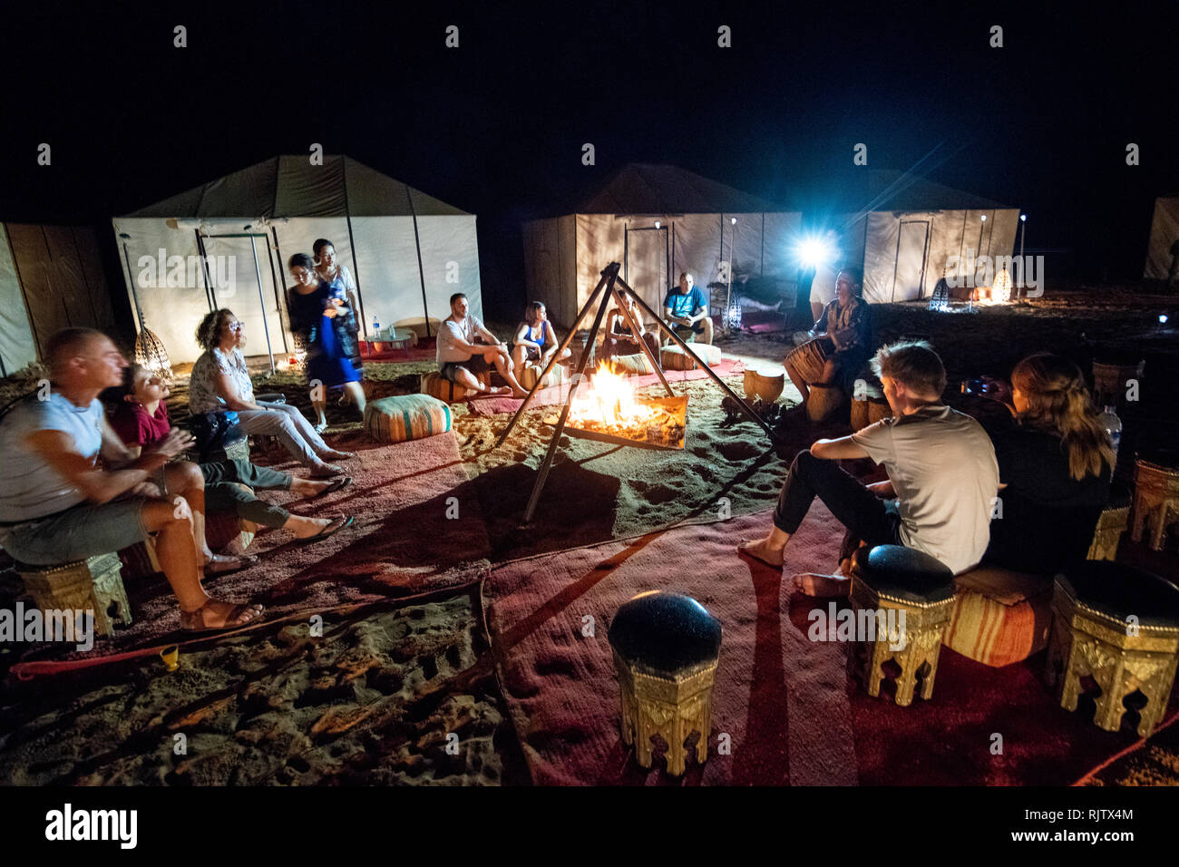 Congregazione delle persone attorno a un fuoco in campeggio, Merzouga, Marocco Sahara Desert - Erg Chabbi dune Foto Stock