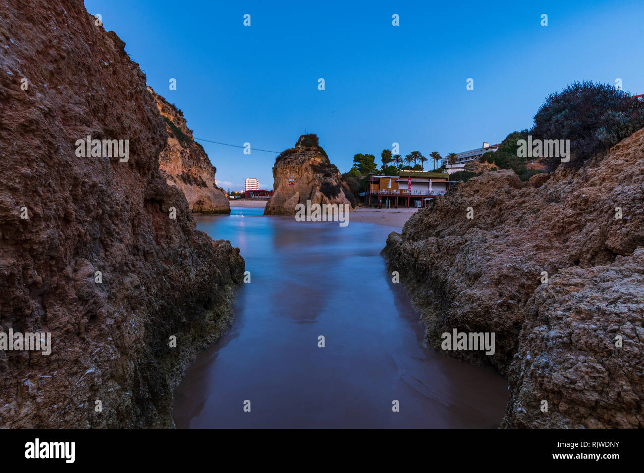 Guardando attraverso le formazioni rocciose verso il mare e il cielo chiaro al tramonto, Alvor, Algarve, Portogallo, Europa Foto Stock