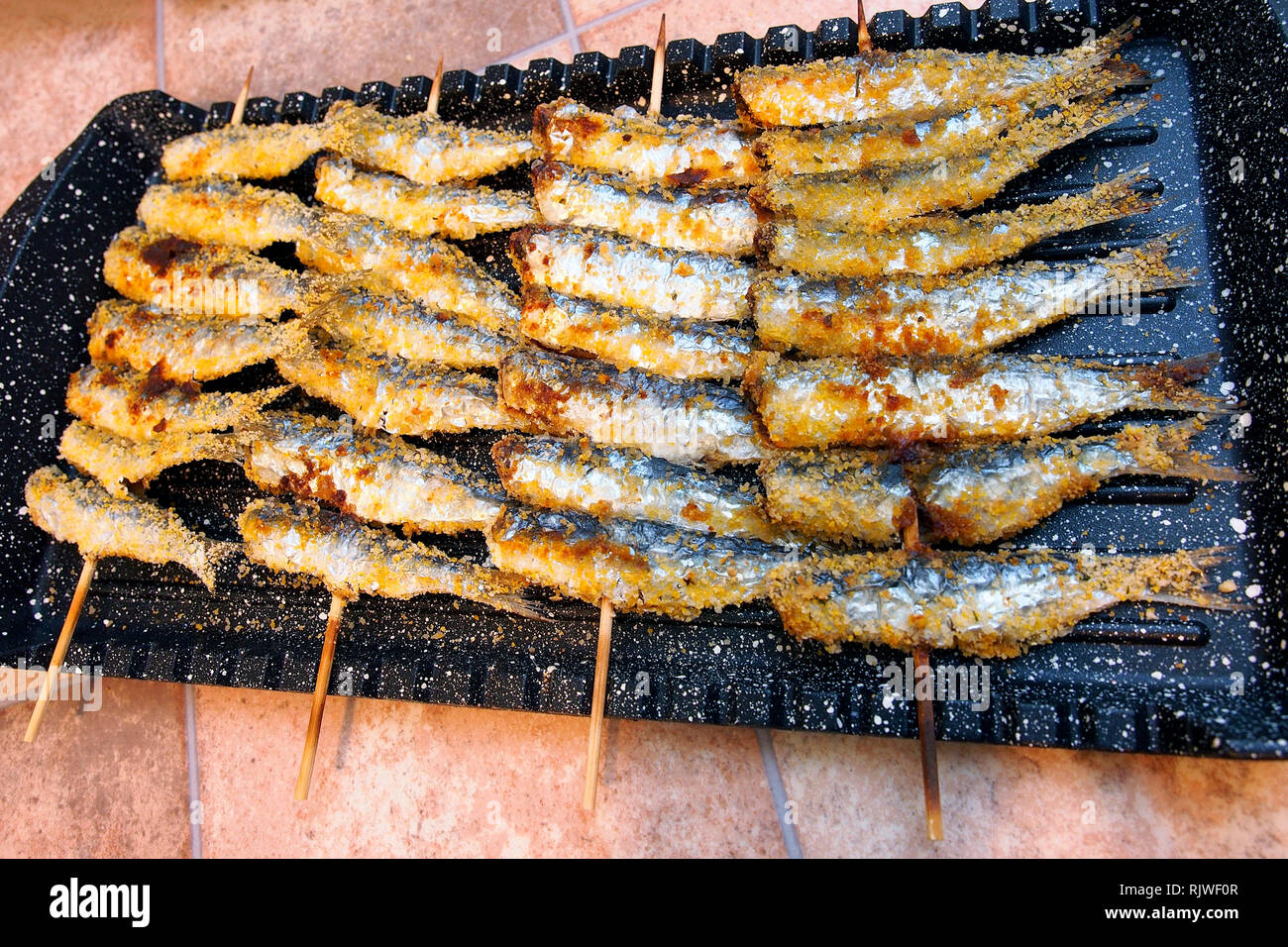Street market alimentare. Spiedini di pesce alla griglia con le acciughe. Foto Stock