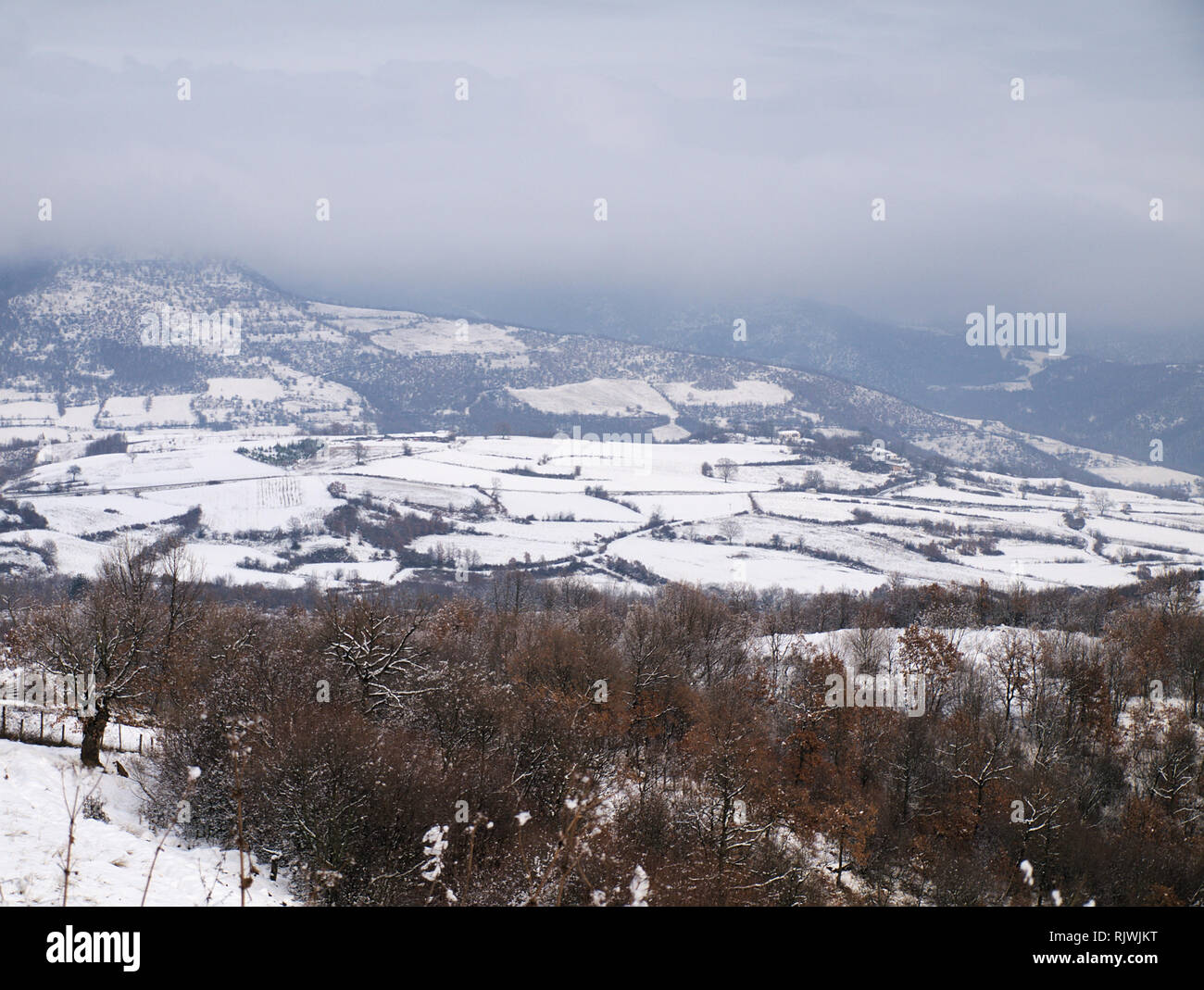 Coperte di neve e di campo montagne sotto un cielo nuvoloso in Macedonia Centrale Grecia Foto Stock