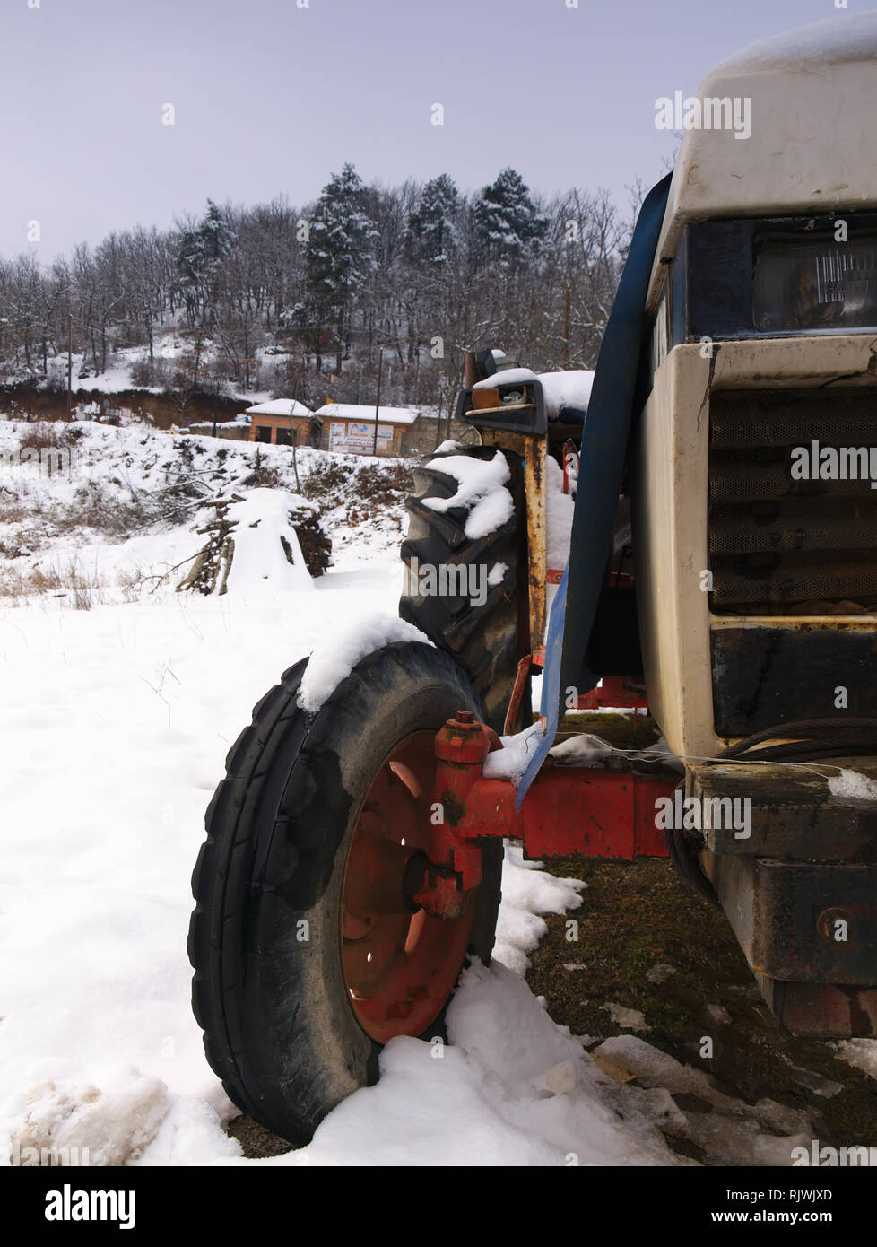 Rusty rurale dettaglio automobile in coperta di neve campo con alberi e cielo molto nuvoloso in background Foto Stock