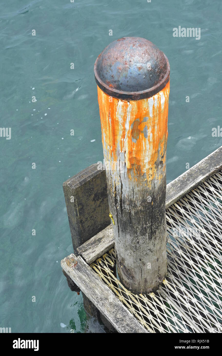 Weathered big bore pontile in legno con palo di ferro arrugginito tappo sulla parte superiore. Foto Stock