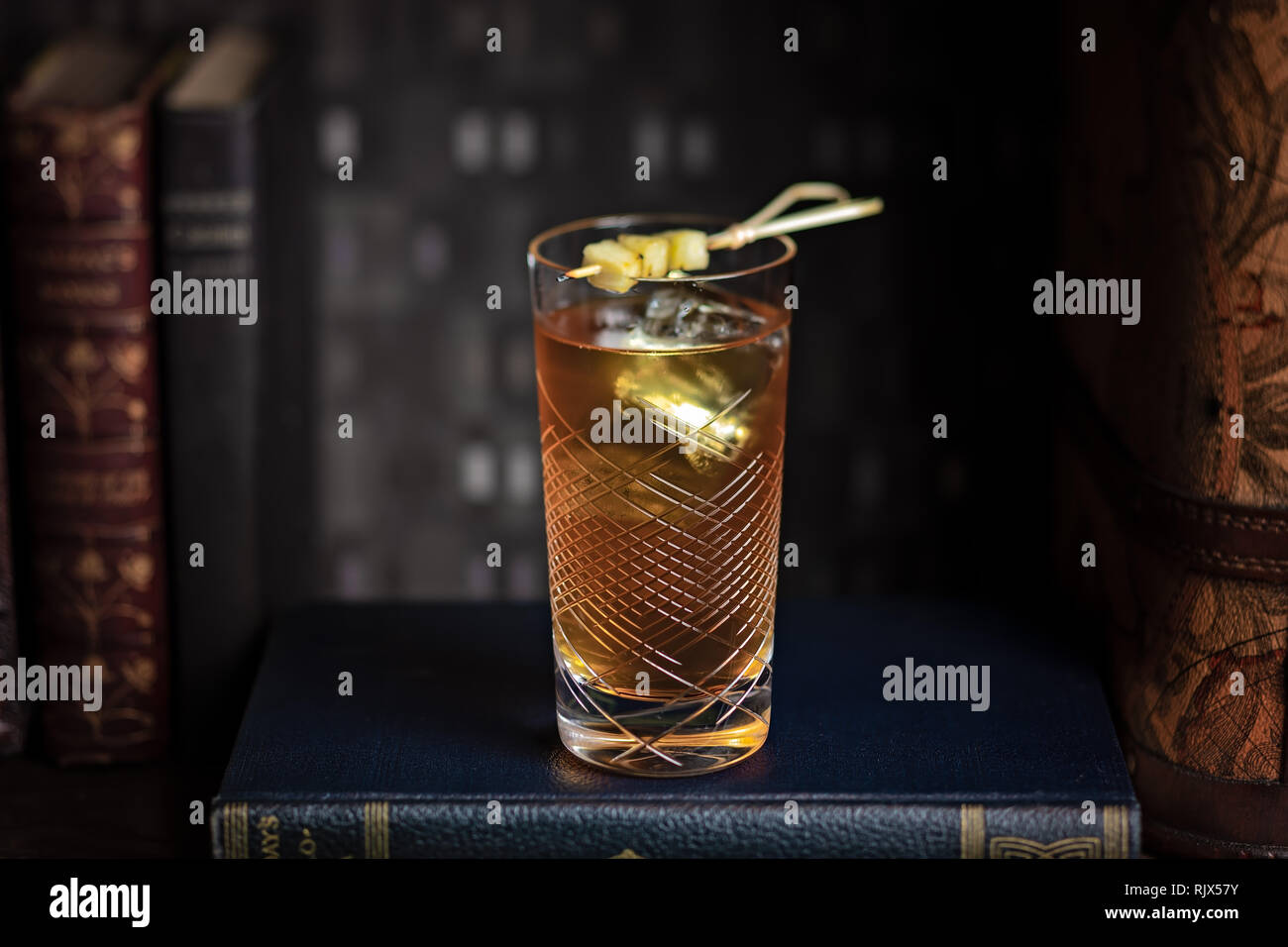 Un cocktail alto servito in un bicchiere di highball collocato all'interno la biblioteca Foto Stock Un cocktail alto servito in un bicchiere di highball collocato all'interno la biblioteca Foto Stock