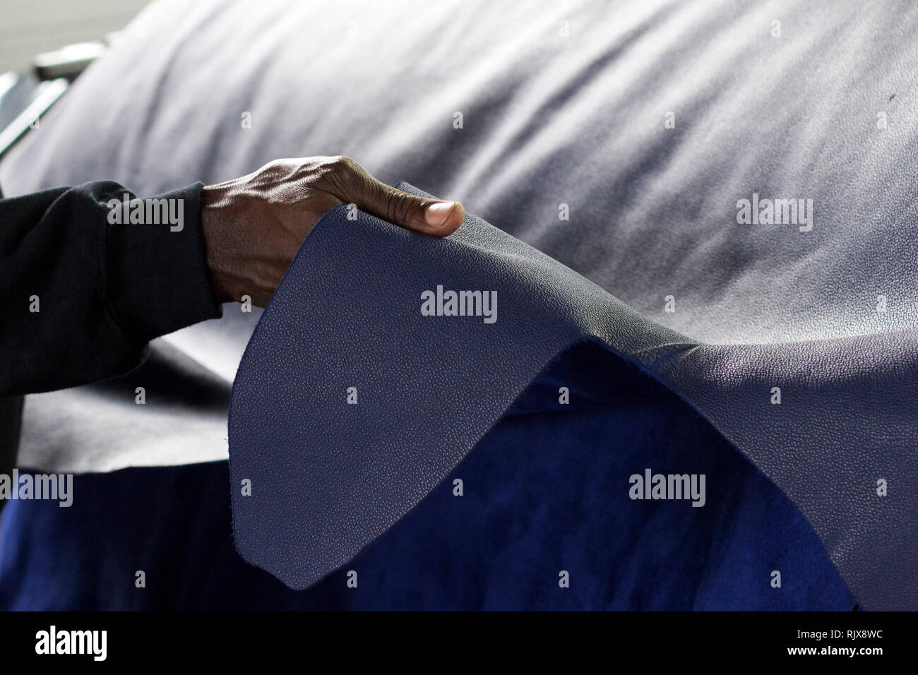 Primo piano orizzontale di un uomo nero tenendo un foglio di pelle blu Foto Stock