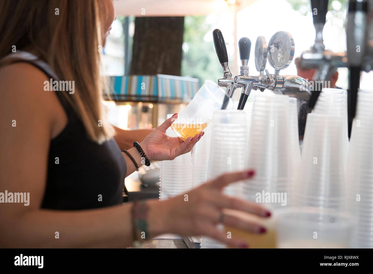 Primo piano di una giovane donna mentre lei sta toccando una birra bionda in una molla festa all'aria aperta. Foto Stock