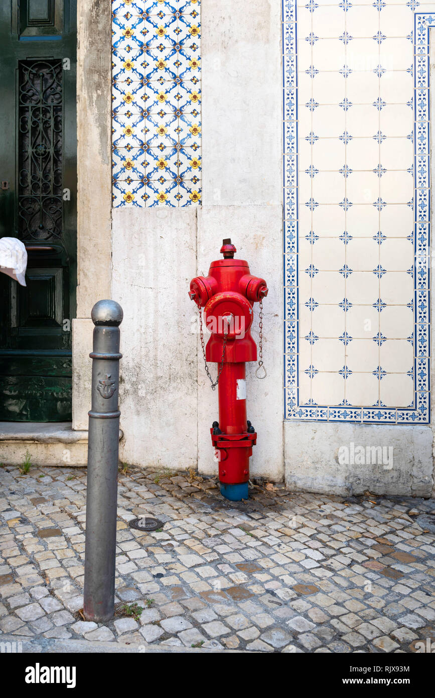 Un idrante rosso davanti a una bianca facciata storica di Lisbona Foto Stock