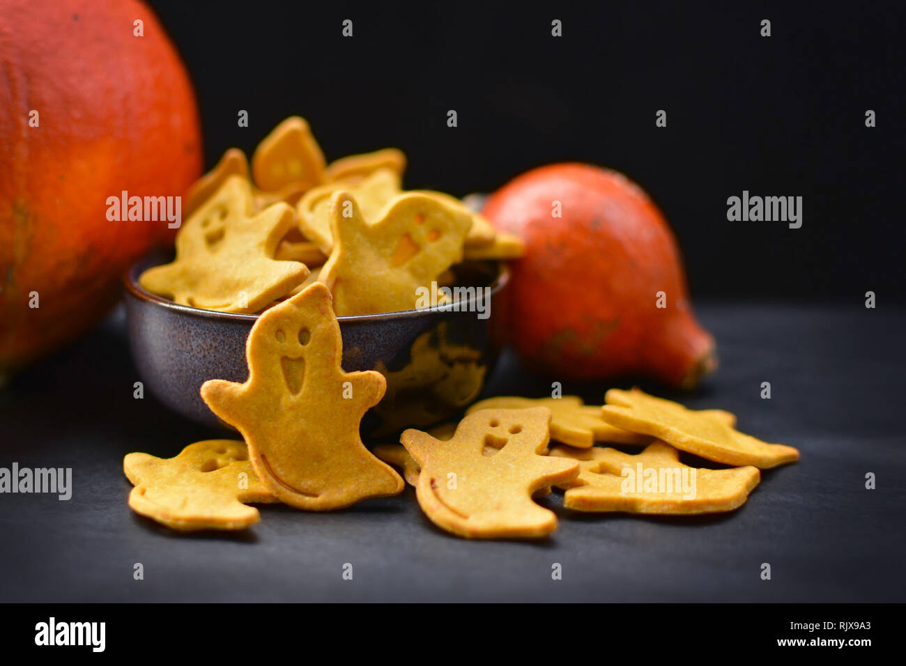 Giallo Fantasma spettrale a forma di biscotti di Halloween con zucche arancione scuro su sfondo nero Foto Stock