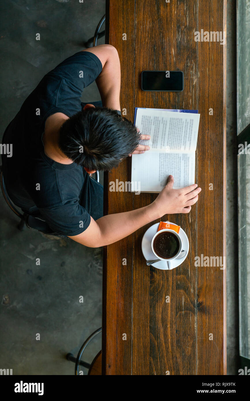 Libro di lettura mentre si beve il caffè Foto Stock