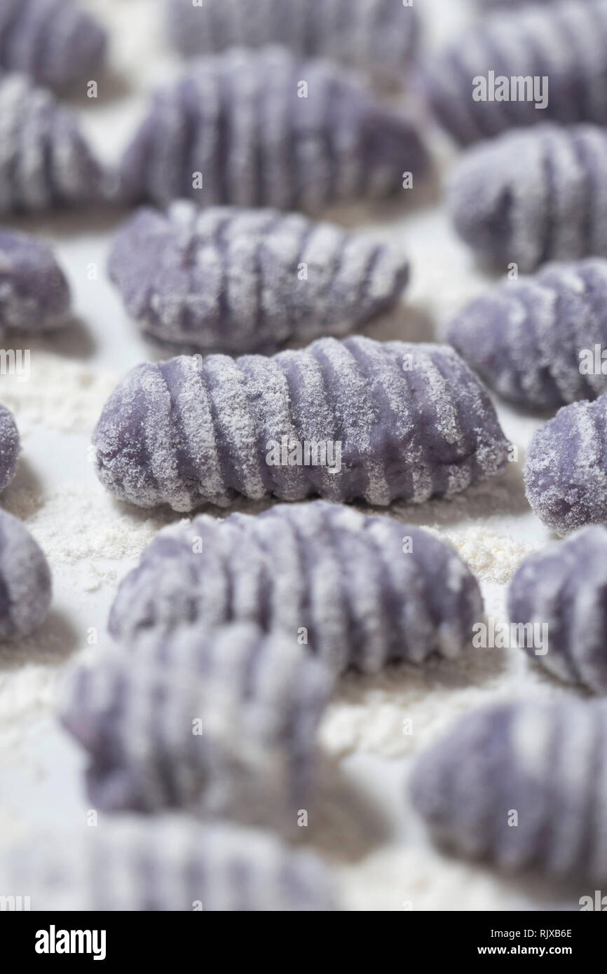 Macro shot di materie gnocchi viola su un bianco porcellana vintage vassoio. Violetta italian gnocchi fatti con patate viola. Foto Stock