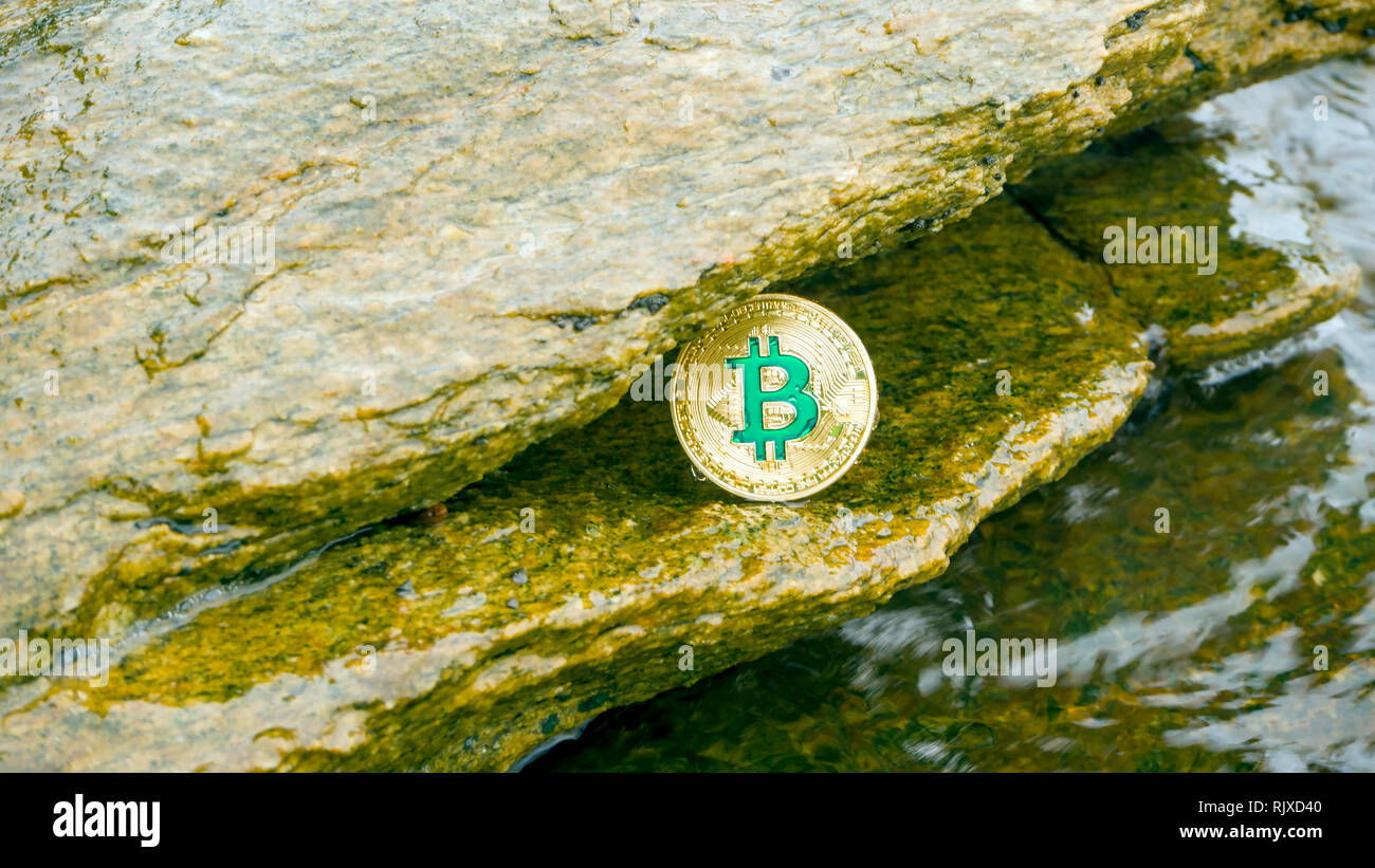 La moneta in oro di Bitcoin risiede nella roccia con le onde del mare. Bitcoin è un moderno modo di scambiare questo crypto moneta è un comodo mezzo di pagamento da me Foto Stock