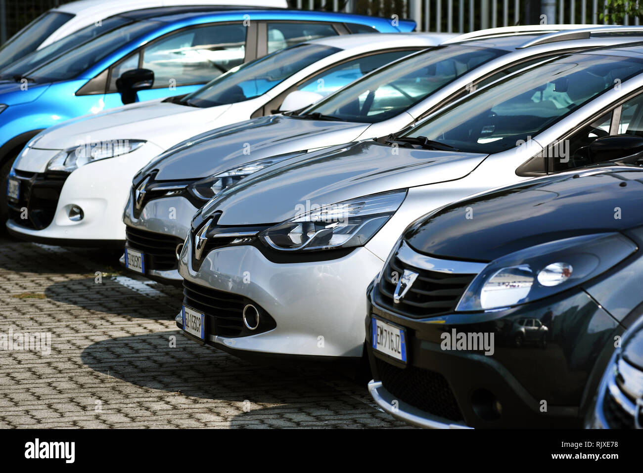Linea di automobili parcheggiate su un lastricato area di parcheggio in una vista ravvicinata sulla parte anteriore del cofano o del cofano in una linea diagonale Foto Stock