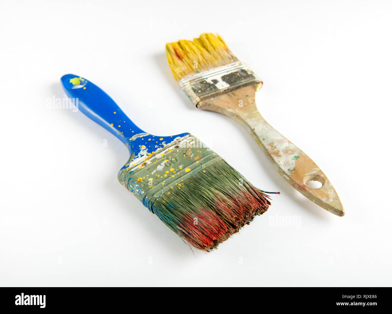Due vecchi usati in legno spazzole di vernice colorata di rosso e giallo su sfondo bianco in una decorazione ed il concetto di DIY Foto Stock