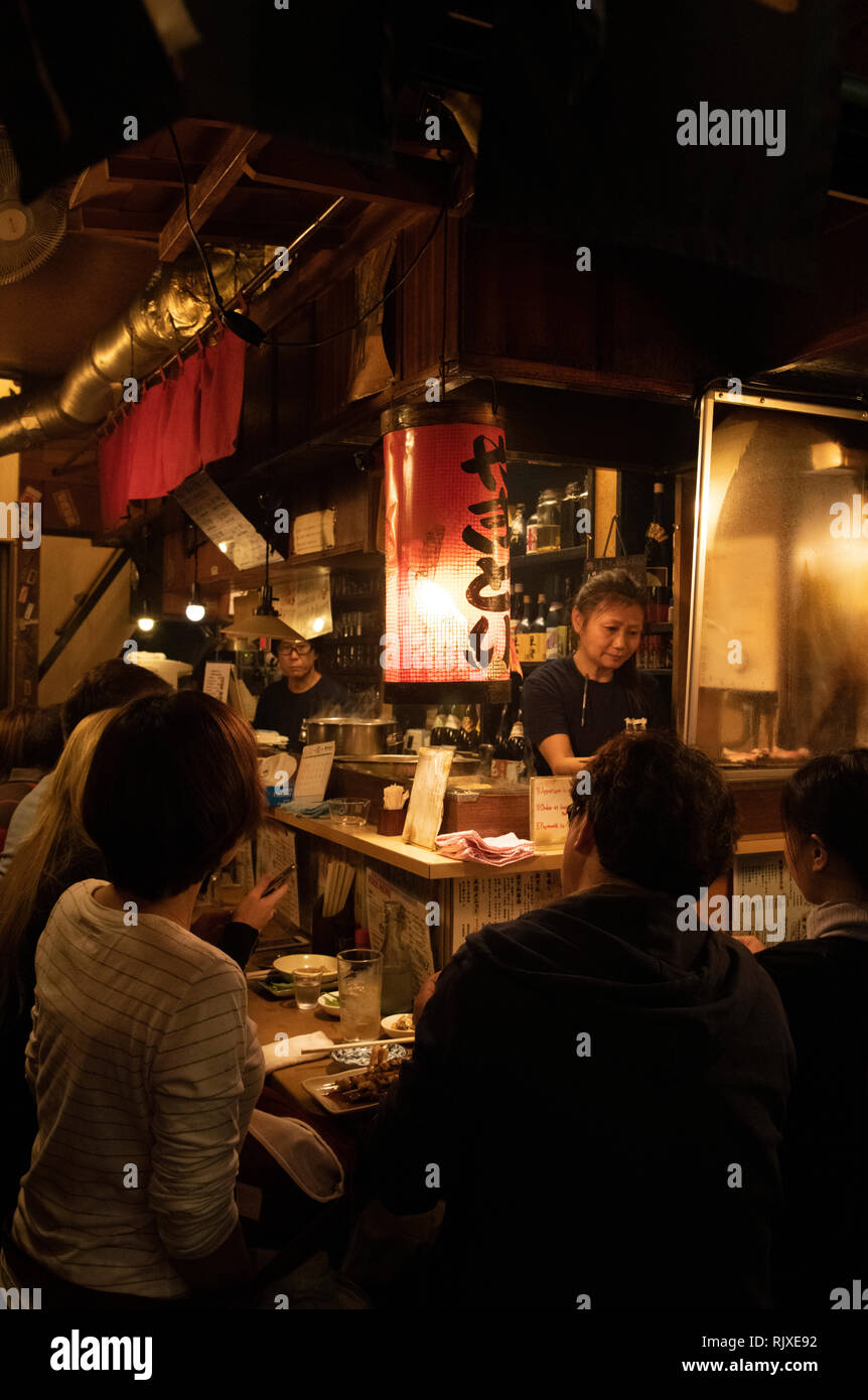 Persone in un piccolo ristorante in Omoide-yokocho, un vicolo di piccoli ristoranti che servono yakatori in Shinjuku, Tokyo, Honshu, Giappone Foto Stock