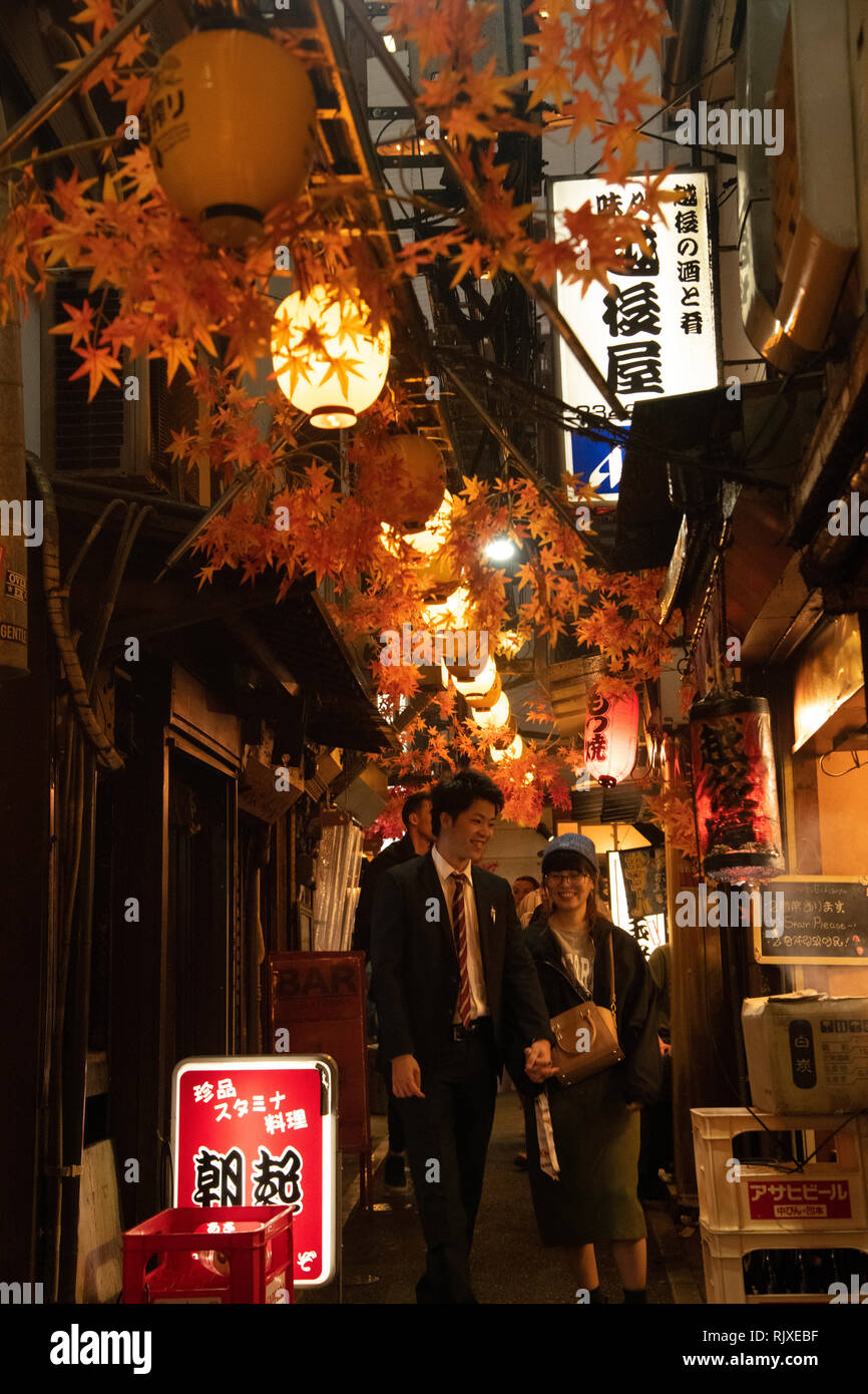 Un giovane a piedi attraverso Omoide-yokocho, un vicolo di piccole yakatori ristoranti a Shinjuku, Tokyo, Honshu, Giappone Foto Stock