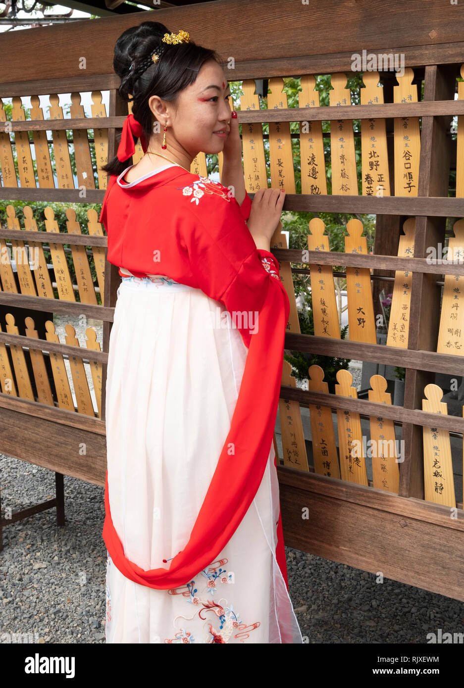 Una donna giapponese che indossa un kimono in posa accanto alla preghiera tavole a Fushimi Inari Shrine, Kyoto, Giappone Foto Stock