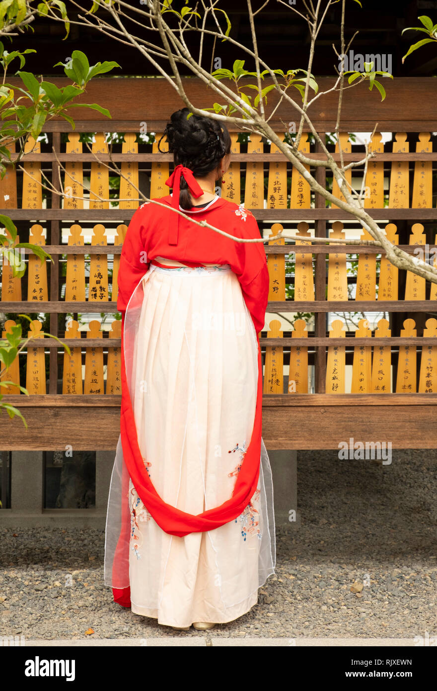 Una donna nel tradizionale abito giapponese guardando la preghiera tavole a Fushimi Inari Shrine, Kyoto, Giappone Foto Stock