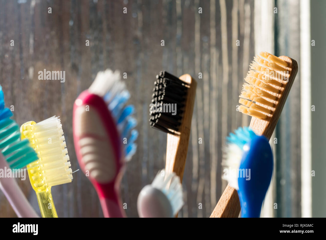 Vista ingrandita di eco-friendly spazzolino da denti di bambù accanto alla finestra nella stanza da bagno Foto Stock