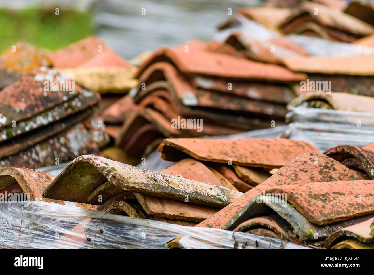 Punto di vista di molte tegole rosse del tetto impilati sul terreno Foto Stock