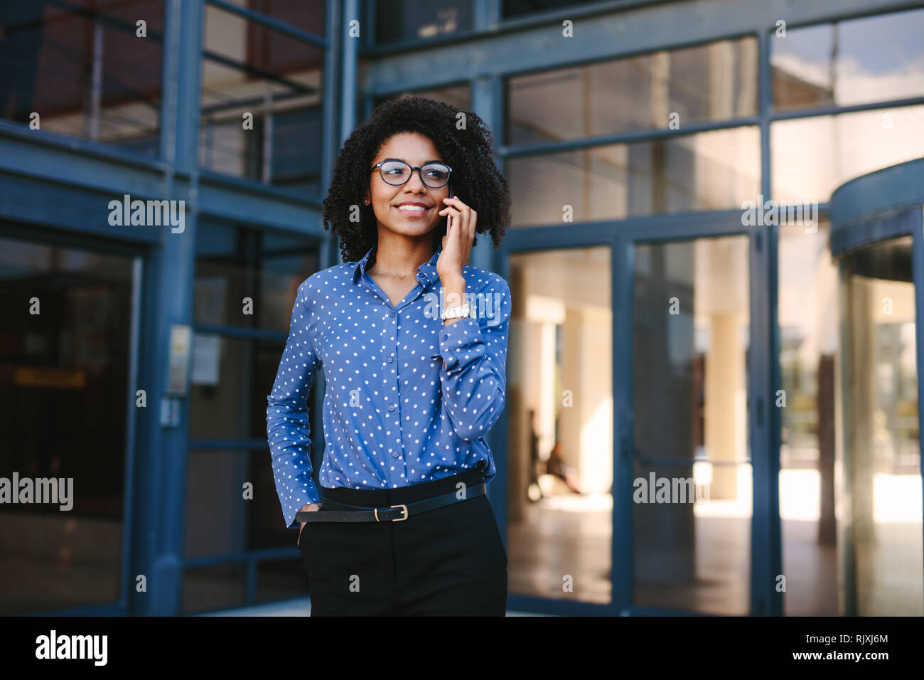donna d'affari in piedi fuori dall'edificio degli uffici che parla al cellulare. professionista aziendale che effettua una chiamata mentre si è all'aperto. Foto Stock