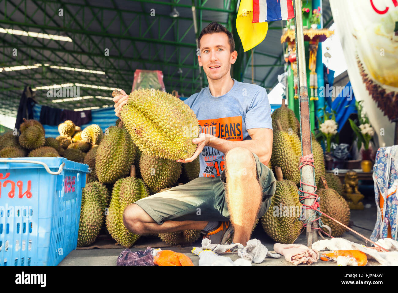 Il viaggiatore dell'uomo tiene in mano la frutta tropicale esotica popolare conosciuta per il relativo odore fetid di sudore / frutti thailandesi: Durian, re dei frutti tropicali Foto Stock