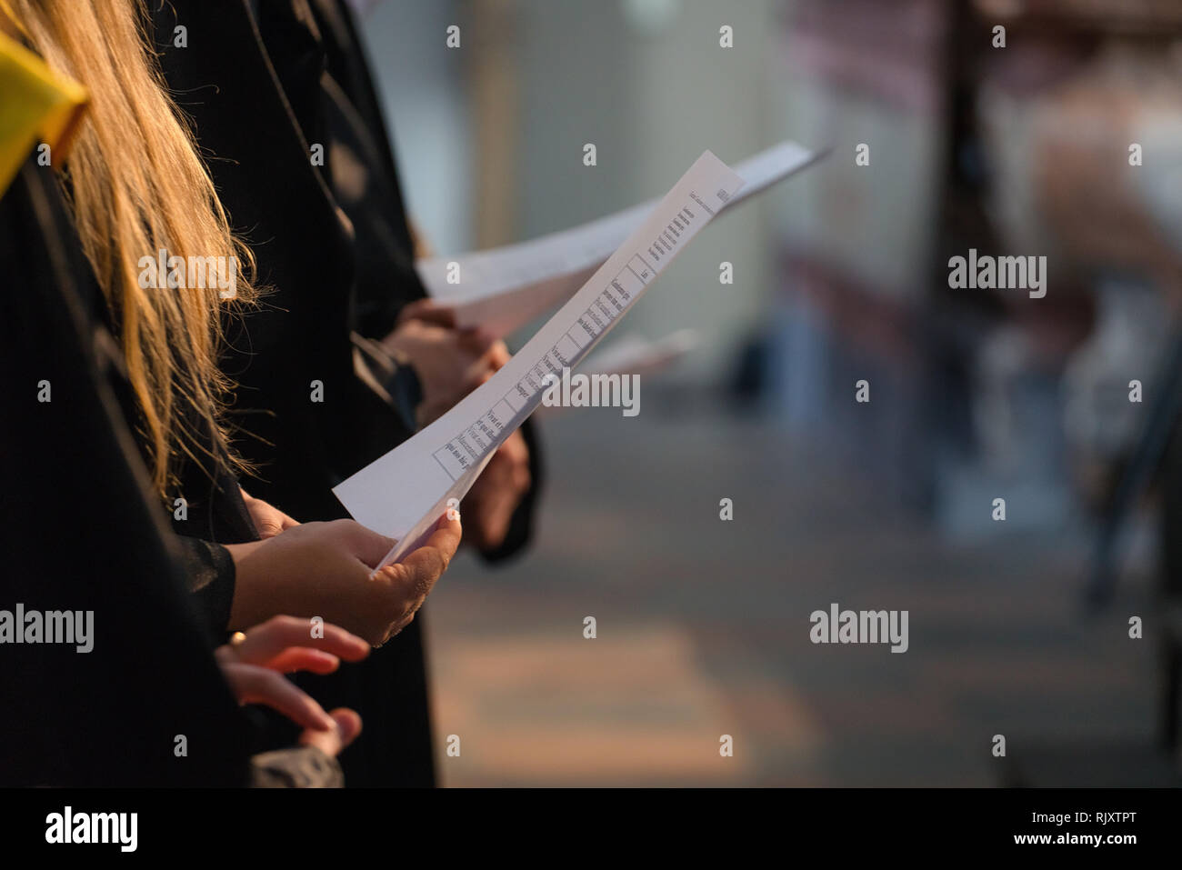 Coro cantanti holding partitura musicale e il canto per studenti il giorno di graduazione in università, college diploma inizio Foto Stock