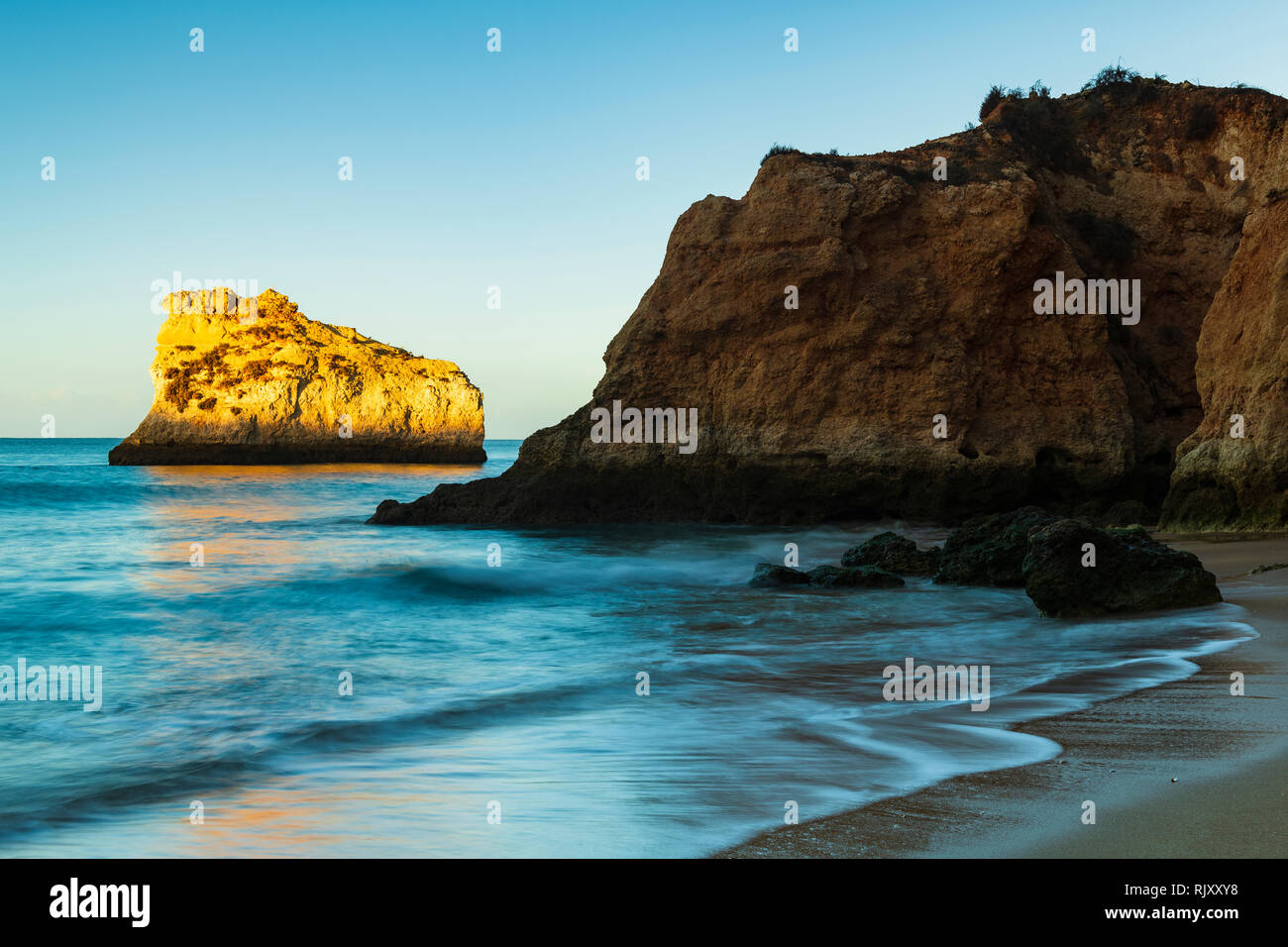 Cielo blu chiaro soleggiato sopra la formazione di roccia in mare, Alvor, Algarve, Portogallo, Europa Foto Stock